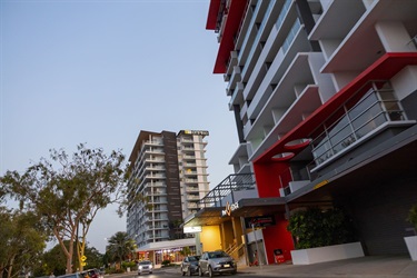 Two modern high-rise apartment buildings sit above a city street at dusk