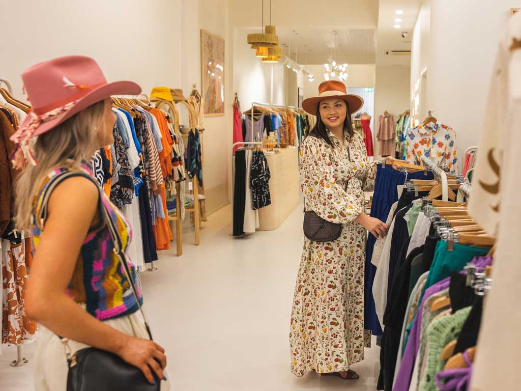 Two women browse through clothing inside a modern and clean shop