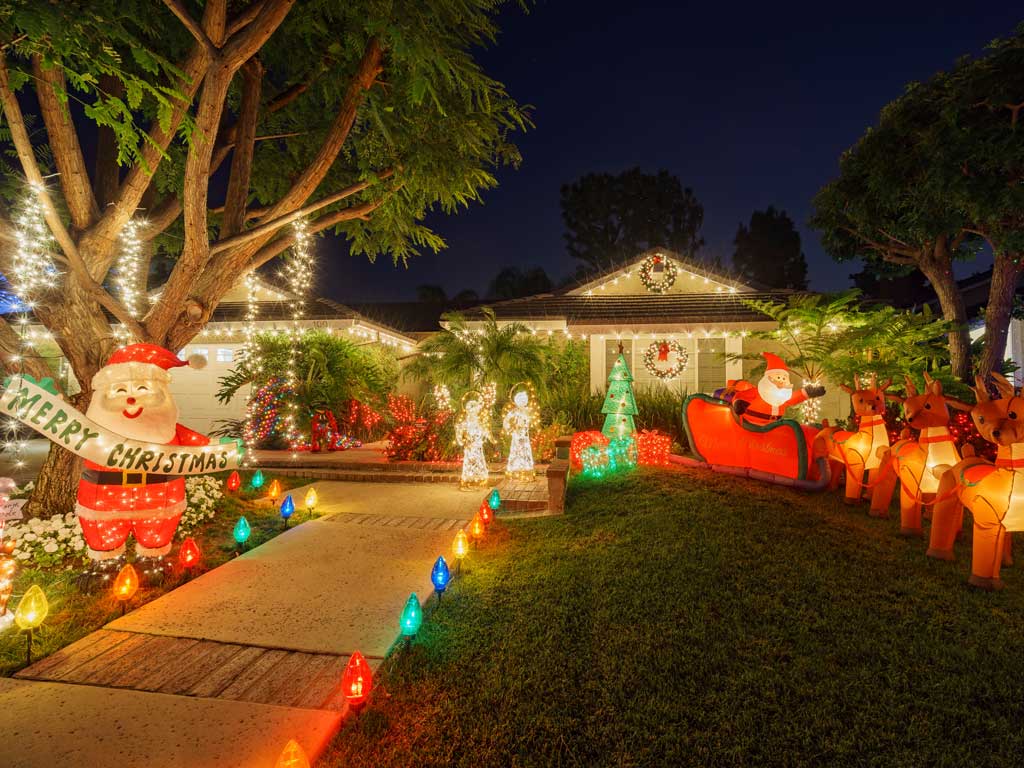A home is decorated in Christmas lights with an inflatable Santa and reindeer on the front lawn
