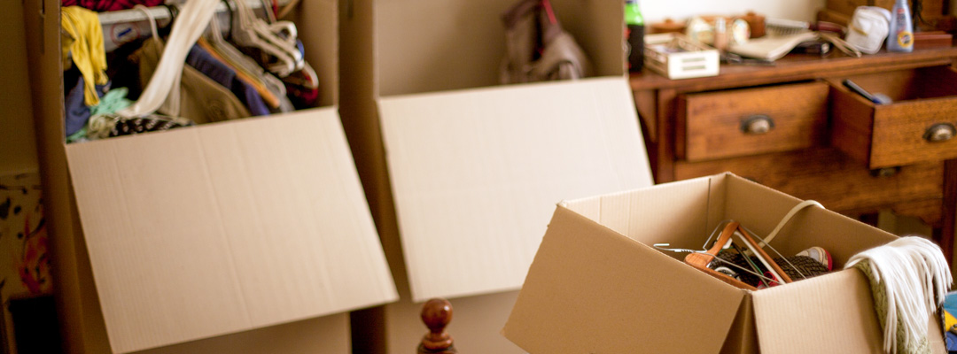 Partially filled moving boxes sit on a bedroom floor