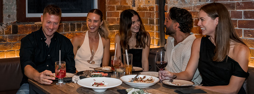 A group of friends enjoy meals and drinks on a night out