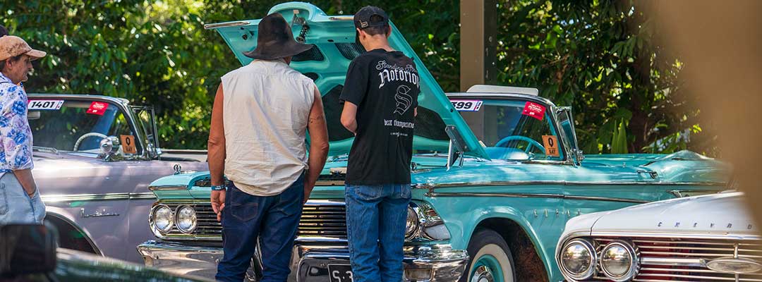 Two men look under the bonnet of a classic ute parked on Rockhampton's riverfront
