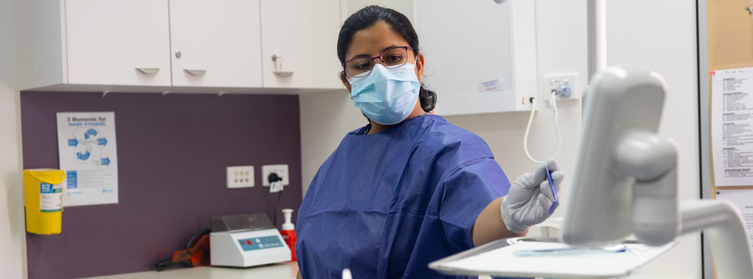 A dentist points to a screen as she discusses results with a patient