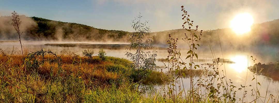 Fog lifts from Mount Morgan No 7 Dam as the sun rises behind mountains