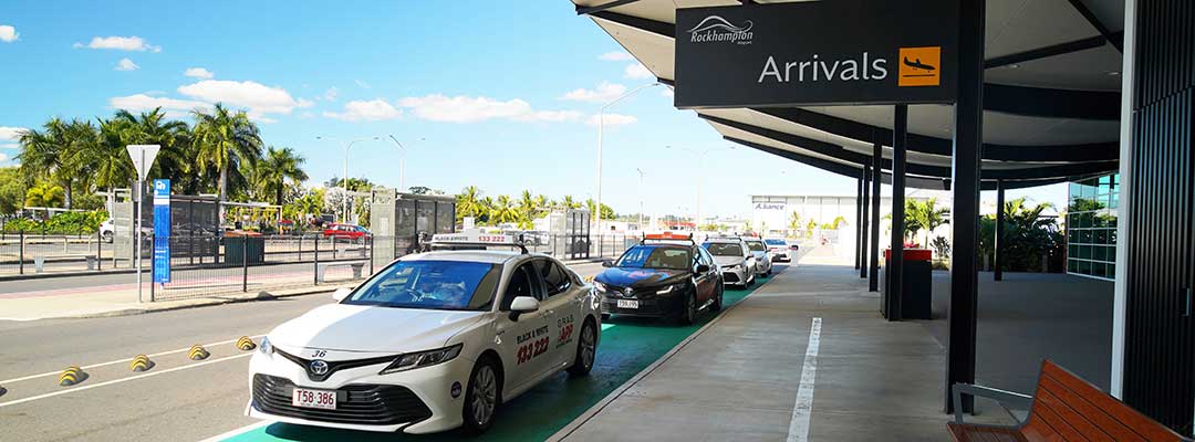 A line of taxis are parked up outside the Rockhampton Airport terminal