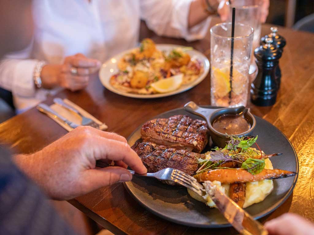 A man eats a meal of steak and vegetables