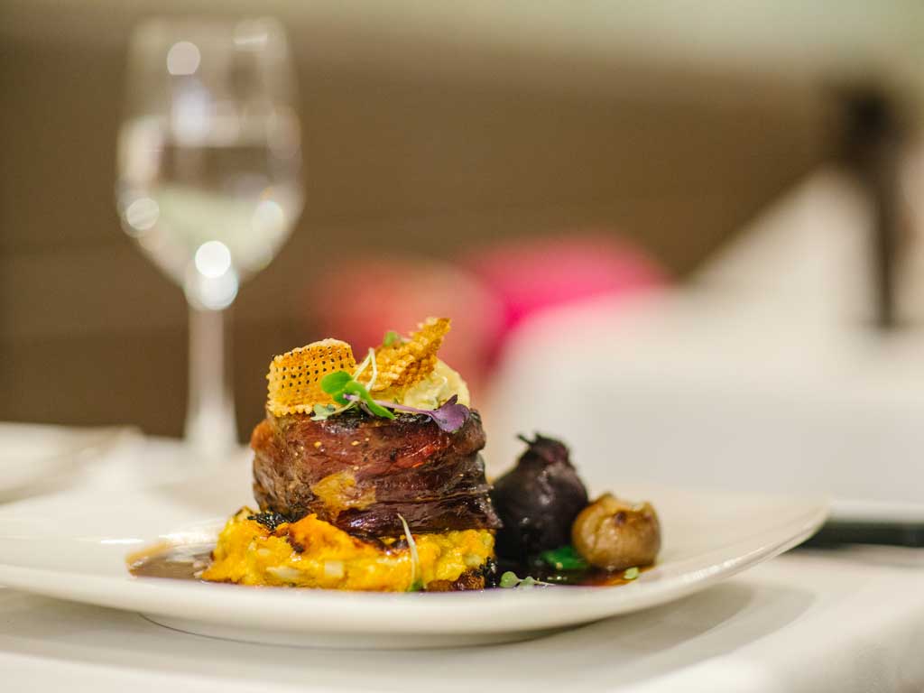 A delicately prepared meal sits on a white place in a high-class restaurant