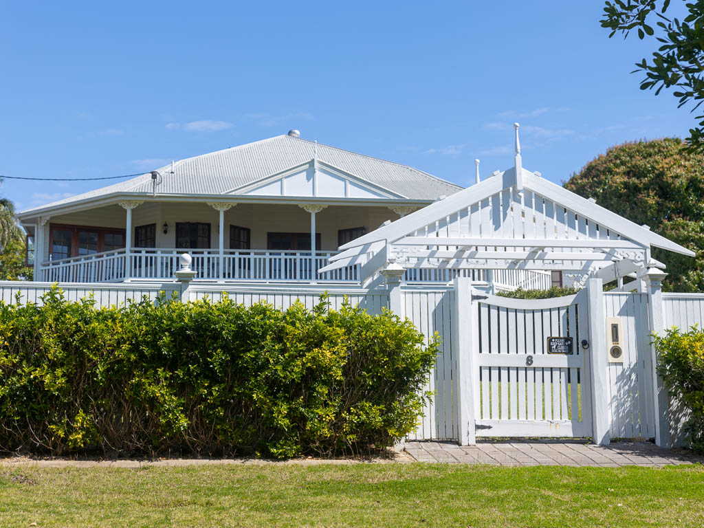 A white picket fence surrounds a luxurious high-set wooden house