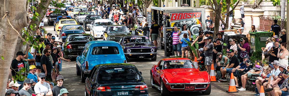 Rows of classic cars drive past crowds of spectators along historic Quay Street in Rockhampton