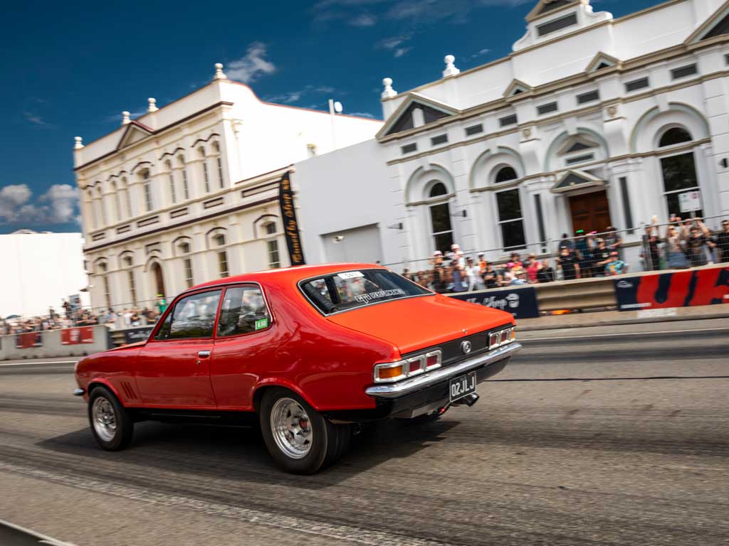 An orange sedan starts a drag race on Rockhampton's historic Quay Street